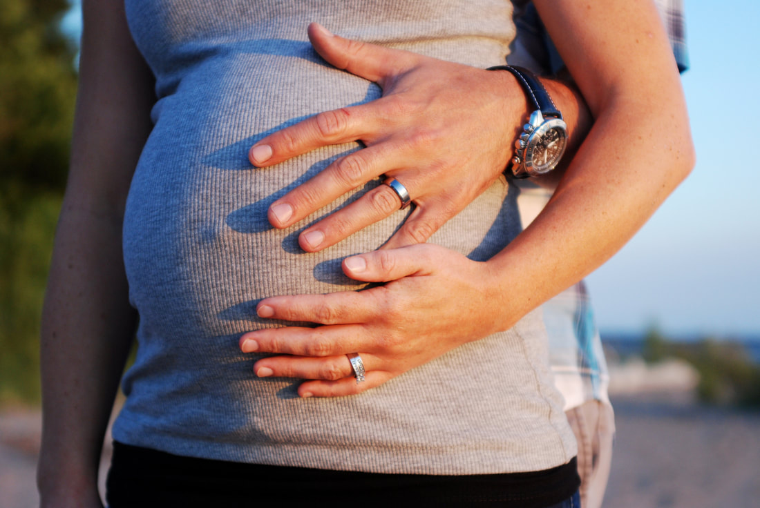 Photo of a pregnant woman with partner's hand on stomach